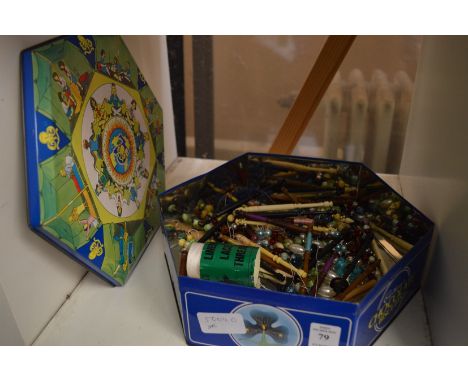A tin of lace bobbins.