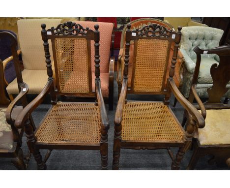 A pair of oak framed armchairs with cane work seats and back panels.
