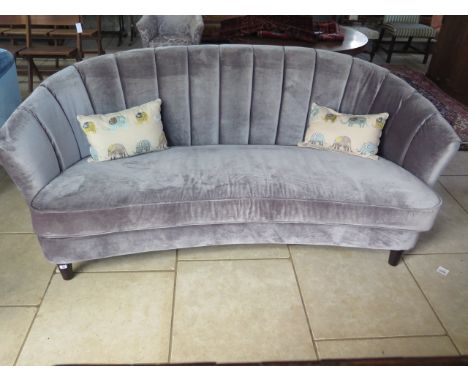 A grey upholstered banana shaped sofa, 90 cm tall x 213 cm wide x 100 cm 
