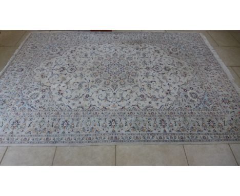 A hand knotted woolen rug with a light blue field 3.5m x 2.47m. Some light wear but generally good. 