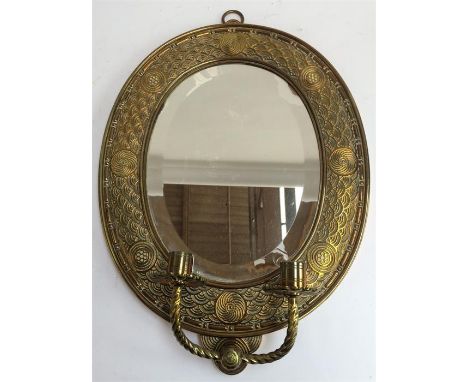 A small oval mirror with two candlestick sconces