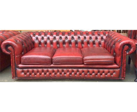 A three seat Chesterfield sofa, upholstered in buttoned oxblood vinyl leather