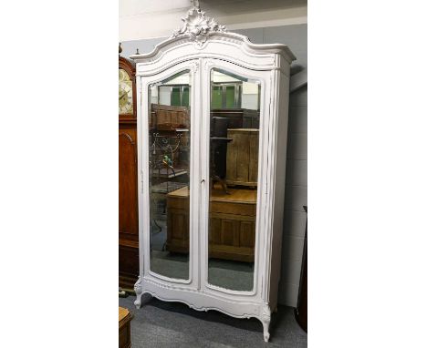 A 20th century white painted armoire mounted by shell decoration, the two doors with full length mirror plates, internally on