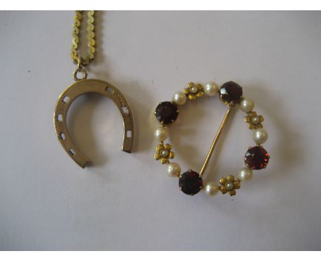 A 9ct gold horseshoe pendent on an associated chain. A yellow metal seed pearl and ruby brooch. (2).  