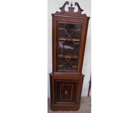 An Edwardian mahogany standing corner cupboard with a broken swan neck pediment above an astragal glazed door, the base with 