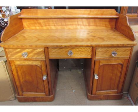 A satin walnut desk, with a raised back and shelf above a central drawer, two other drawers and two cupboards