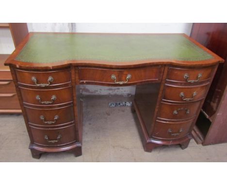 A 20th century walnut desk, the green leather inset top above a central drawer and two pedestals of four drawers on bracket f