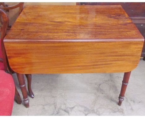 A Victorian mahogany Pembroke table with a rectangular top and drop flaps on ring turned tapering legs