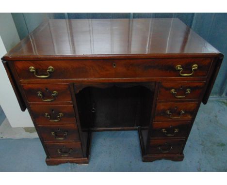 A rectangular mahogany kneehole desk with drop flap to the sides, nine drawers with brass swing handles all on bracket feet, 