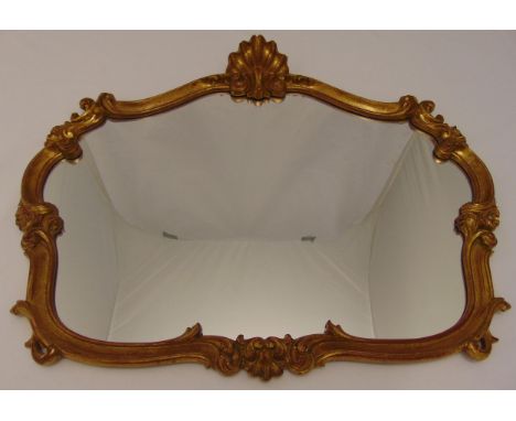 A shaped oval gilded wooden wall mirror carved with scrolls and shells, 70 x 81cm