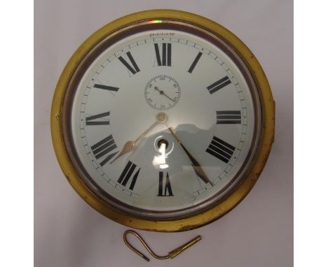 A brass circular ships clock mounted on a wooden plinth, white enamel dial with Roman numerals, 23cm diameter