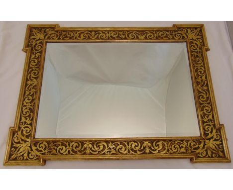 A shaped rectangular bevelled edge wall mirror mounted in a carved low relief gilded wooden frame, 80.5 x 106cm