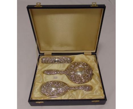 A cased hallmarked silver dressing table set comprising a hand mirror, a hair brush and a clothes brush