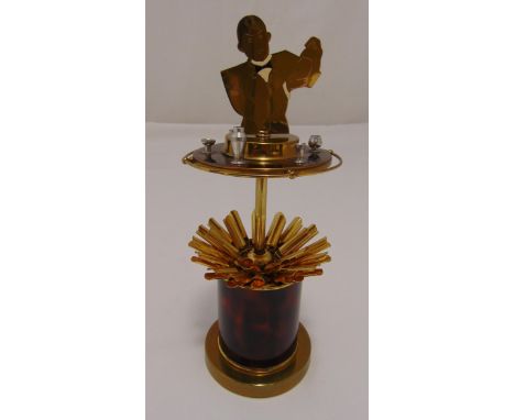 A novelty Art Deco gilded metal and enamel cigarette dispenser, the pull up top in the form of a bar tender making cocktails