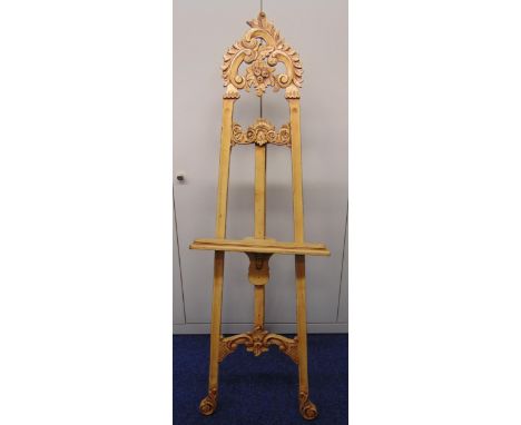 An Art Nouveau style blonde wood picture easel, carved with scrolls and leaves, 190 x 59.5cm