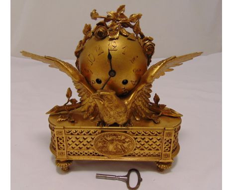 A French gilt metal mantle clock of globular form supported by an eagle on shaped rectangular base with trellis sides on turn