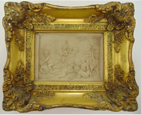 A framed Enrico Braga style carved plaque depicting putti playing in a garden with an inset Perfugium Regibus coin to the ver