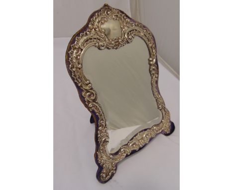 An Edwardian hallmarked silver dressing table mirror, shaped rectangular chased with leaves, flowers and scrolls with hinged 