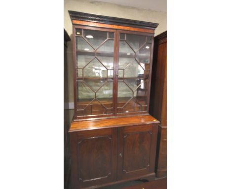 An early 19th Century mahogany and Kingwood banded bookcase, the upper section fitted nest of ten drawers enclosed astragal m