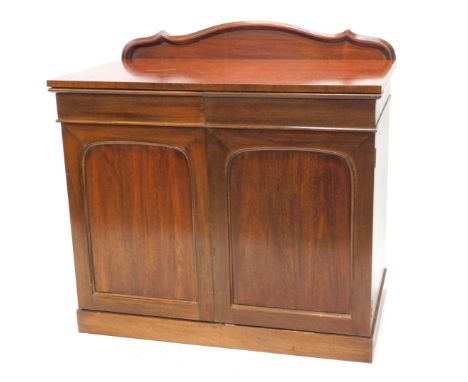 A mahogany serving buffet or sideboard, the top with a moulded raised back, above two panelled doors enclosing part fitted in