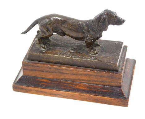 An Elkington &amp; Co bronze sculpture of a Dachshund, standing on a rectangular base with stepped oak plinth, 12cm wide over