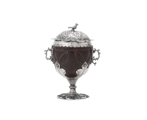 
	
		A SILVER MOUNTED COCONUT CUP 
		UNMARKED, PRESUMABLY SPANISH, CIRCA 1702 
		With a bird finial to the foliate chased dom