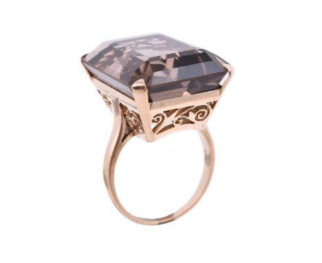 
	
		A SMOKEY QUARTZ DRESS RING 
		The step cut smokey quartz with canted corners, to a pierced scrolled gallery, stamped 10k