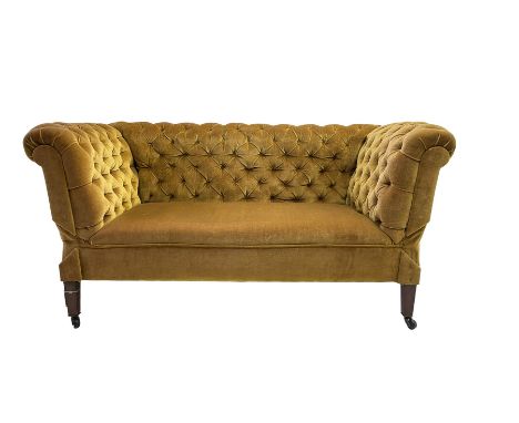 Early 20th century drop-arm chesterfield settee, upholstered in buttoned gold velvet fabric with sprung seat, raised on squar