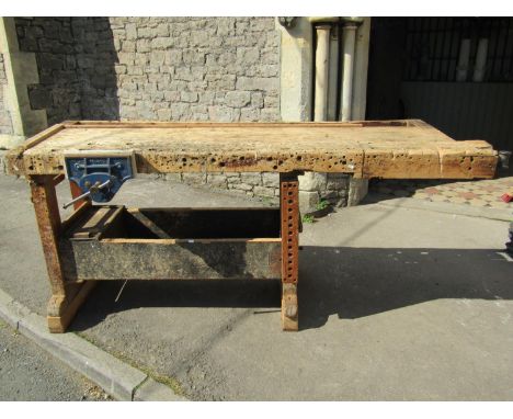 A vintage pine carpenters work bench with two vices raised on rectangular cut supports and sledge feet, raised on further lat