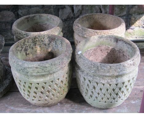 A set of four weathered composition stone circular planters in the form of lattice baskets with repeating entwined Celtic sty