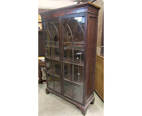 A 19th century mahogany side cabinet freestanding and enclosed by a pair of astragal glazed panelled doors with lancet shaped