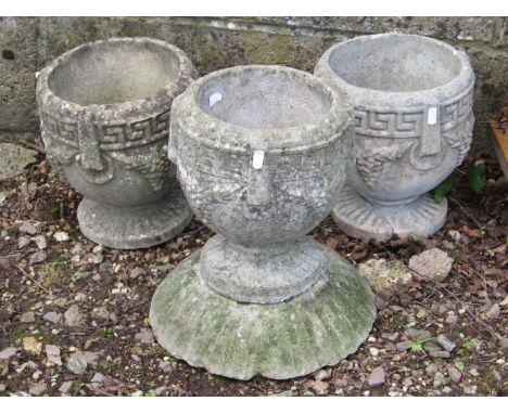 Weathered cast composition stone garden urns of circular form with repeating Greek key ring and fruiting vine detail, one rai