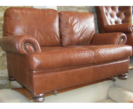 Contemporary two seat sofa upholstered in mid tan coloured leather, on turned supports 