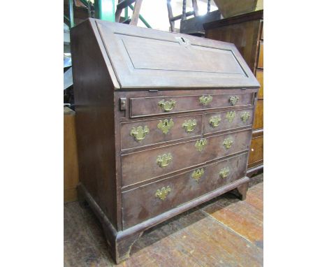 An 18th century oak bureau, the front elevation enclosed by an arrangement of three long and two short drawers, set on bracke