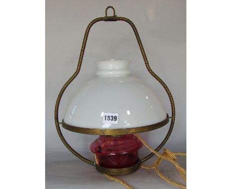A hanging oil lamp with an opaque white glass shade and a red glass font, converted to an electric light. 
