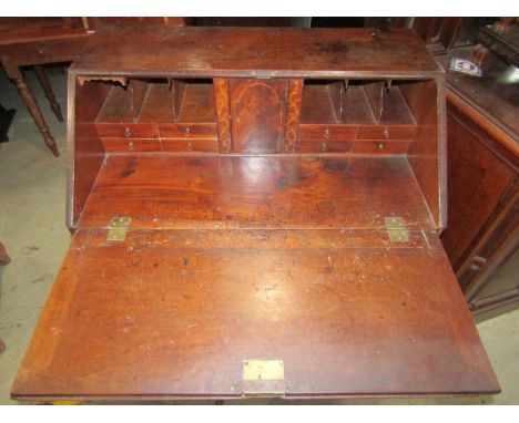 A Georgian mahogany bureau, the fall flap enclosing a fitted interior of small drawers and pigeon holes flanked by central cu