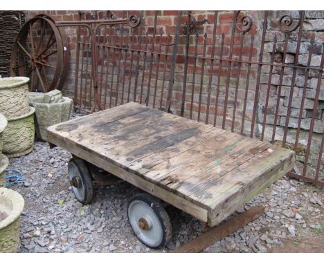 A vintage four wheeled hand cart with front rotating axle, T shaped tubular handle and wooden bed, 127 cm long x 70 cm wide 