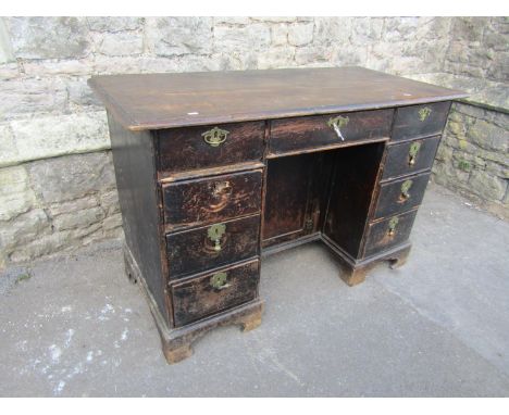 A Georgian oak kneehole writing desk fitted with nine drawers with central recess cupboard and raised on bracket supports, 12