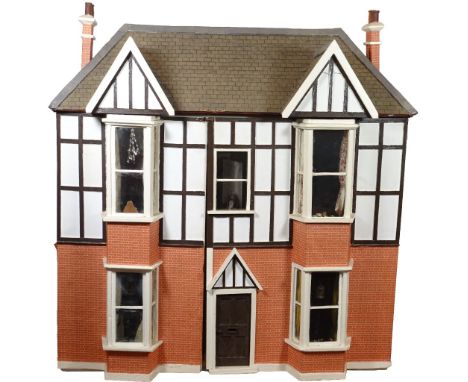 A large Tudor style painted wooden dolls house, English 20th century, the papered red brick and white beamed exterior with hi