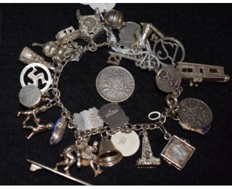 A sterling silver curb link charm bracelet with assorted charms, cuckoo clock, windmill, tape recorder, surfer, Mexican; etc 