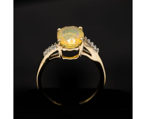 A 9CT YELLOW GOLD OVAL-CUT YELLOW OPAL RING, with diamond-set twist shoulders, boxed.