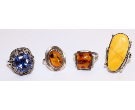 Three amber set silver rings and a ring set with a blue stone and marcasite in a metal box   Condition Report   Click here fo