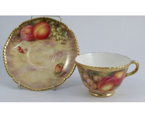 A Royal Worcester tea cup and saucer, the exterior of the cup and the saucer painted with fruit to a mossy background by Free
