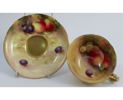 A Royal Worcester tea cup and saucer, the interior of the cup and the saucer painted with fruit to a mossy background by H Ar