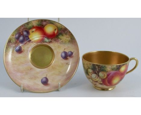 A Royal Worcester tea cup and saucer, the exterior of the cup and the saucer painted with fruit to a mossy background by Free