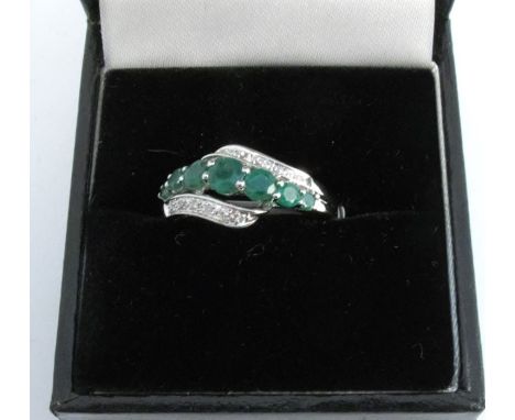 A 9 carat white gold emerald and diamond ring, the seven graduated emeralds with single cuts to either side, finger size N, 3