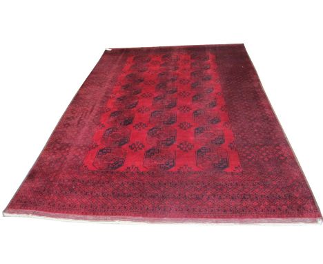 ANTIQUE AFGHAN BASHIR CARPET, 440cm x 310cm, elephant feet gul design and dragon motifs in sapphire on ruby field within Hera