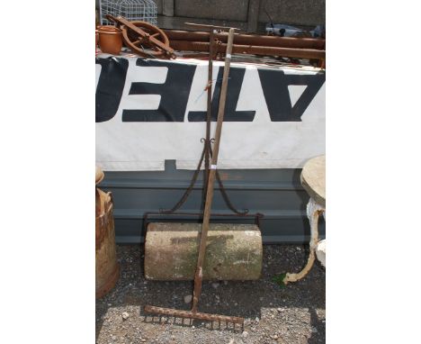 A vintage stone garden roller and garden rake.