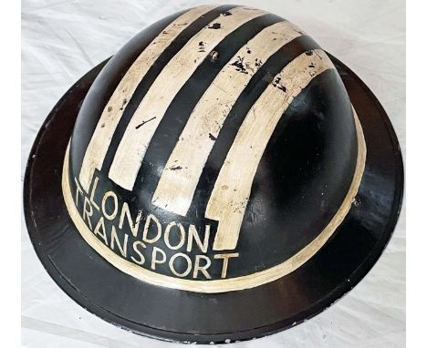 WW2 ARP HELMET lettered 'London Transport' with white blackout stripes and complete with lining and chinstrap. Well-used with