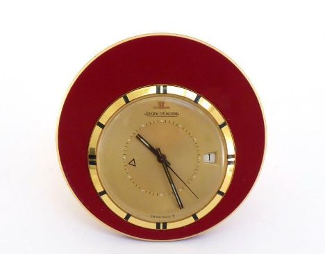 Jaeger LeCoultre, Memovox, a gilt metal and enamel travel clock, no. 1107812, the slim circular burgundy enamel body with off
